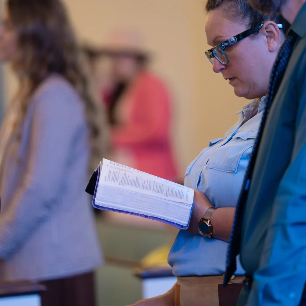 Woman reading an open Bible while standing in the church