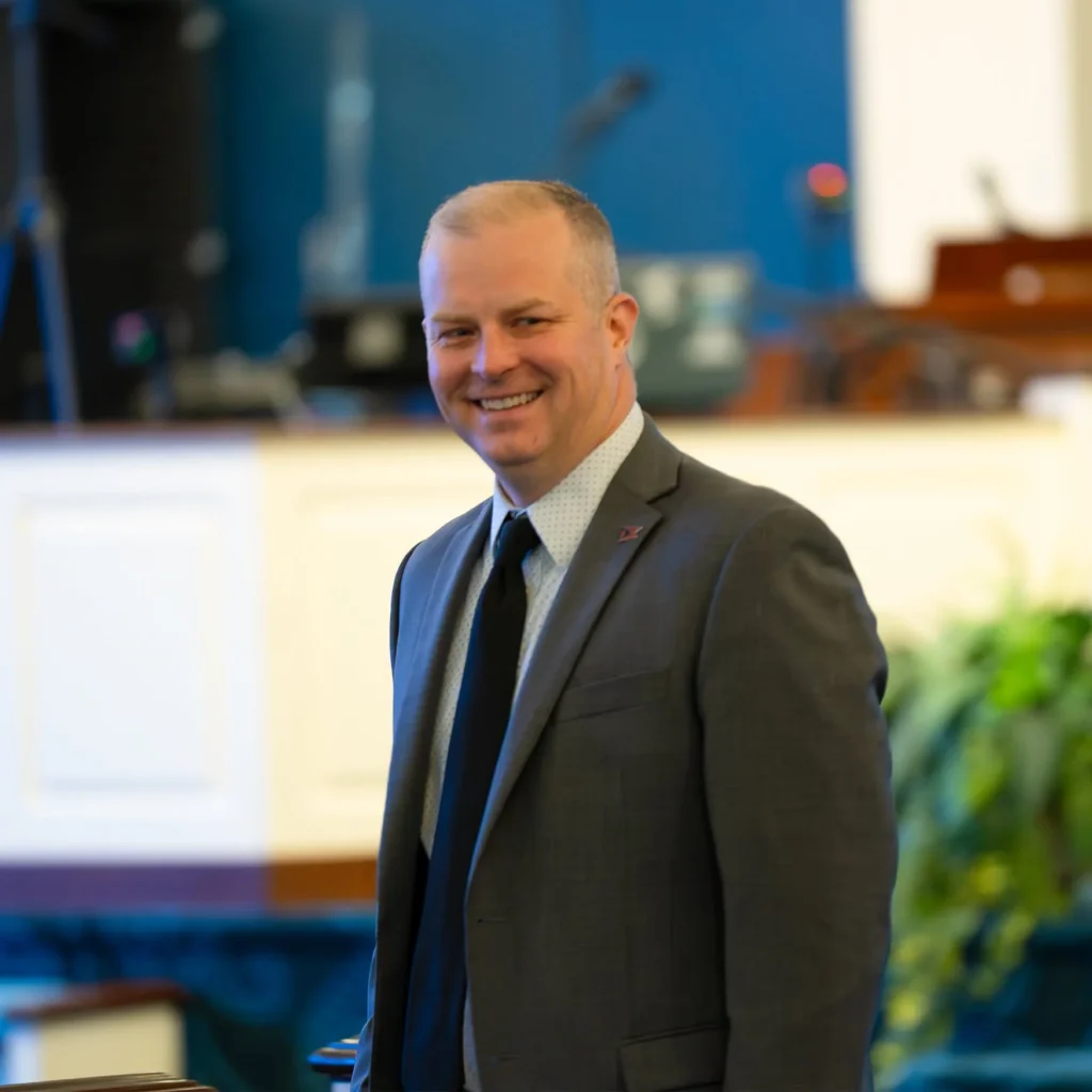 Smiling man in a suit standing near church pews